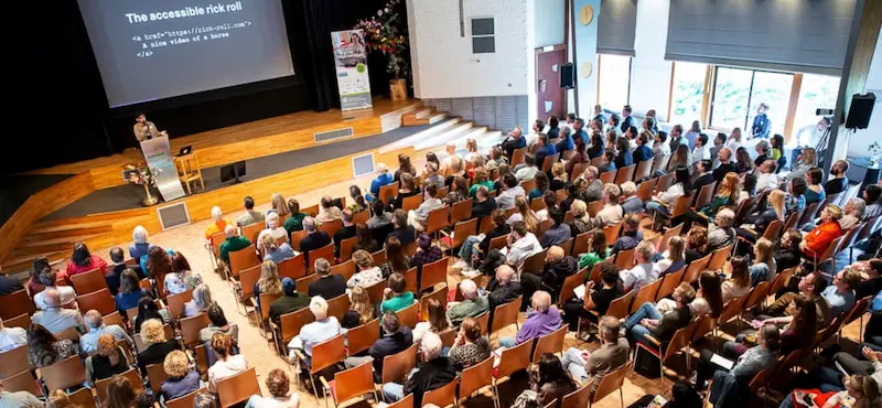 Aerial shot of Heydon speaking in front of a large screen to a seated audience